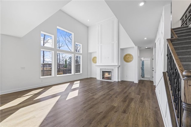 unfurnished living room with a fireplace, dark hardwood / wood-style floors, and a high ceiling