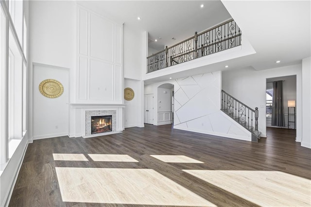 unfurnished living room with dark hardwood / wood-style flooring, a fireplace, and a high ceiling