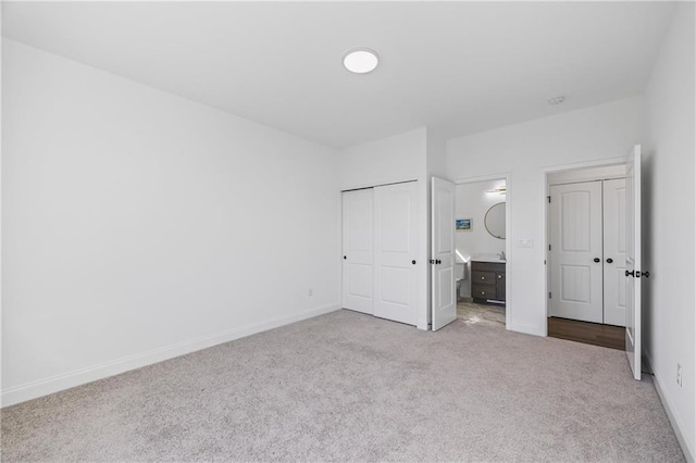 unfurnished bedroom featuring ensuite bathroom and light colored carpet