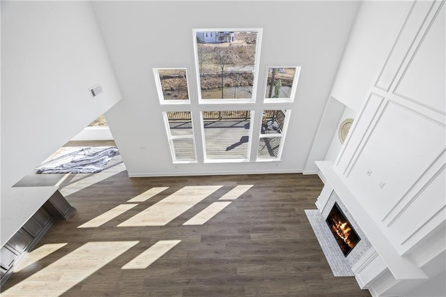 unfurnished living room with dark hardwood / wood-style flooring and a towering ceiling