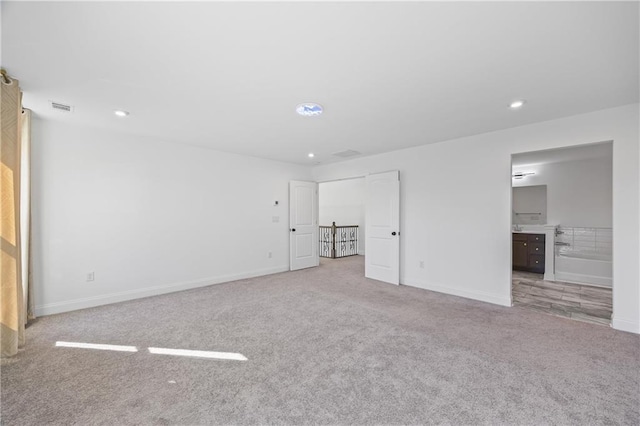 unfurnished bedroom featuring light colored carpet and connected bathroom