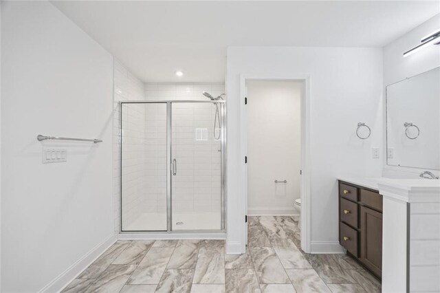 bathroom featuring vanity, toilet, and a shower with shower door