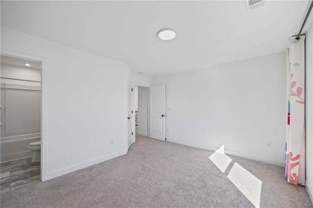 unfurnished bedroom with light colored carpet and connected bathroom