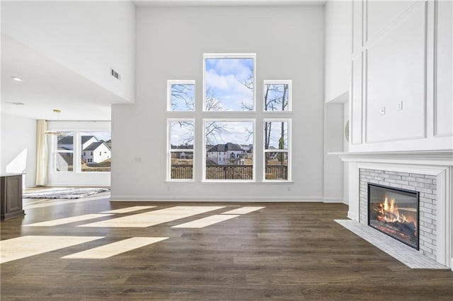 unfurnished living room featuring dark hardwood / wood-style flooring, a fireplace, and a high ceiling