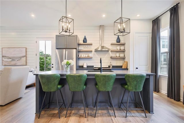 126 Chestnut Cir, Atlanta, GA 30342 - kitchen featuring freestanding refrigerator, a chandelier, wall chimney exhaust hood, open shelves, and a kitchen island with sink