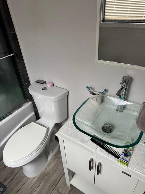 full bathroom with vanity, enclosed tub / shower combo, and toilet