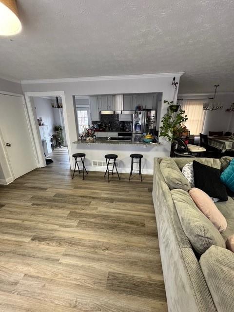 living room featuring ornamental molding, wood-type flooring, and a textured ceiling