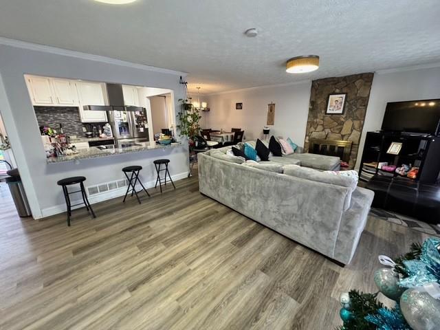 living room featuring ornamental molding, wood-type flooring, a fireplace, and a textured ceiling