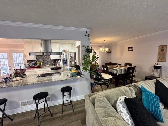 kitchen featuring pendant lighting, stainless steel fridge with ice dispenser, and ornamental molding