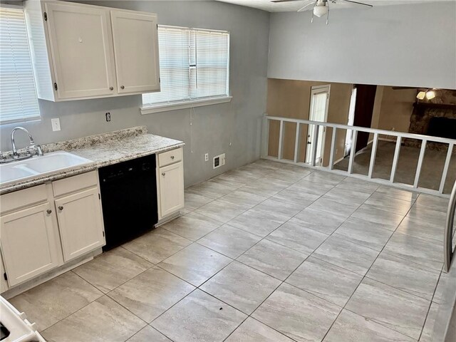 kitchen with light tile patterned floors, stainless steel fridge, ceiling fan, a large fireplace, and white cabinets