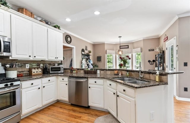 242 Sandhurst Ct, Suwanee, GA 30024 - kitchen featuring appliances with stainless steel finishes, a sink, light wood finished floors, white cabinets, and ornamental molding