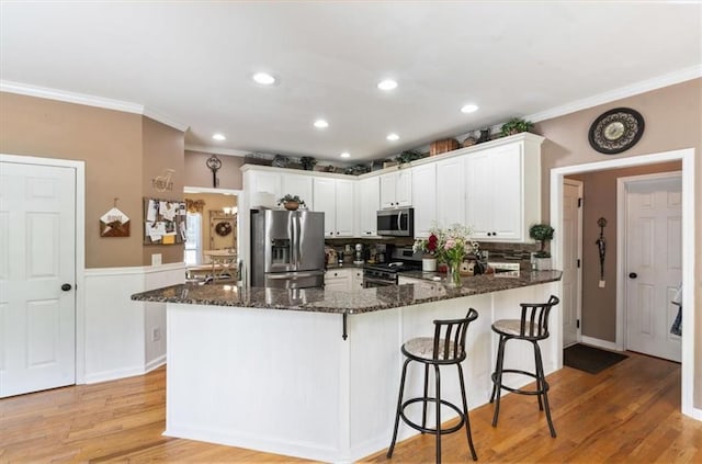 242 Sandhurst Ct, Suwanee, GA 30024 - kitchen featuring appliances with stainless steel finishes, crown molding, a peninsula, dark stone countertops, and white cabinetry