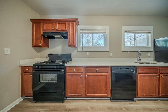 kitchen with light countertops, light wood-style floors, a sink, under cabinet range hood, and black appliances