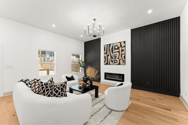 living room featuring a chandelier, a fireplace, and light hardwood / wood-style flooring