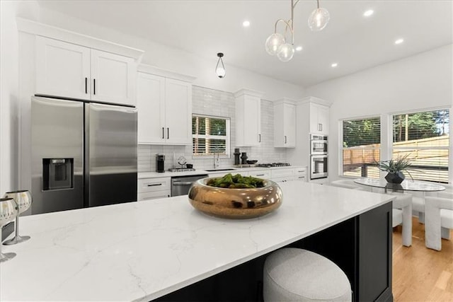 kitchen with white cabinets, appliances with stainless steel finishes, and hanging light fixtures