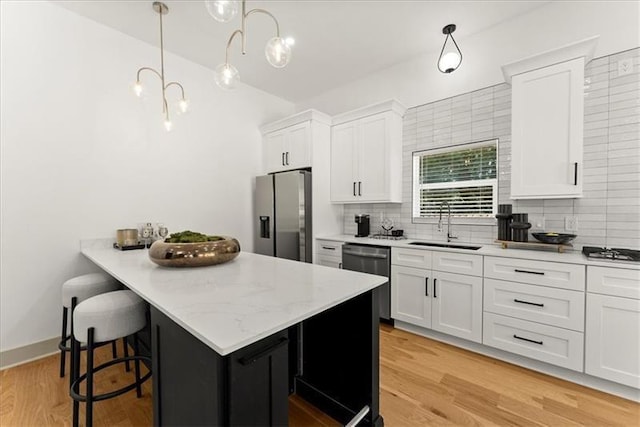 kitchen featuring white cabinetry, sink, decorative light fixtures, decorative backsplash, and appliances with stainless steel finishes