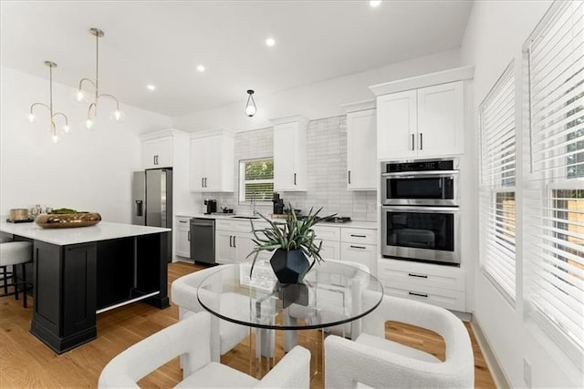 kitchen featuring decorative backsplash, stainless steel appliances, decorative light fixtures, a center island, and white cabinetry