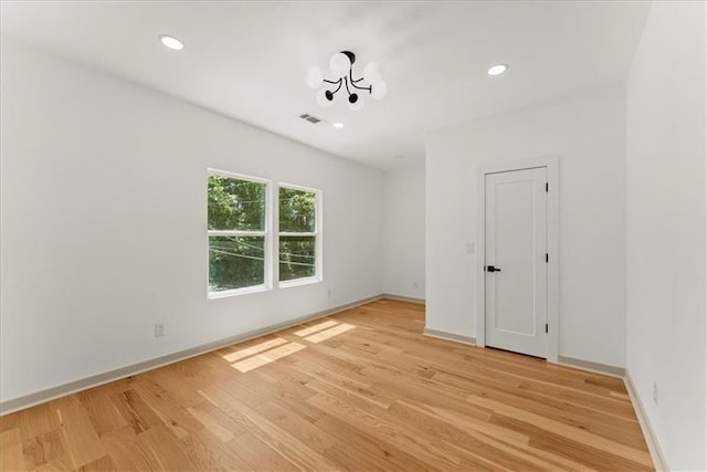 empty room with light hardwood / wood-style floors and a notable chandelier