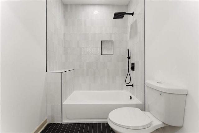 bathroom with toilet and tiled shower / bath