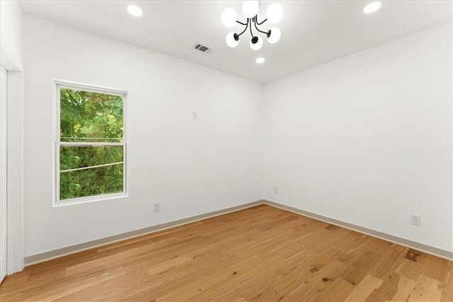 unfurnished room with light wood-type flooring and an inviting chandelier