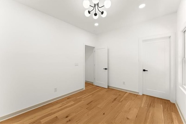 spare room with light wood-type flooring and an inviting chandelier