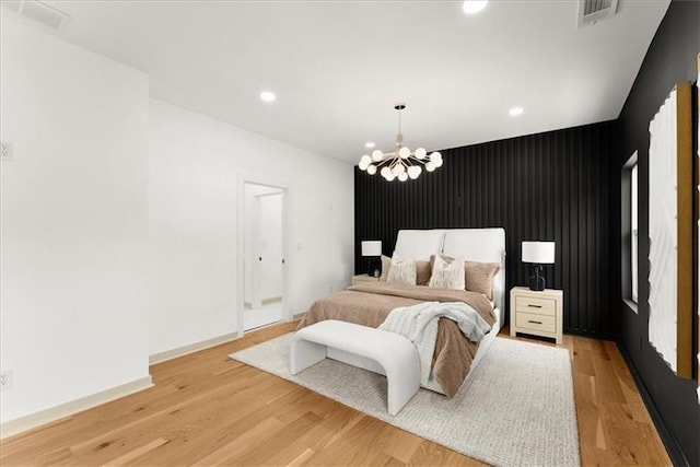 bedroom with light wood-type flooring and an inviting chandelier