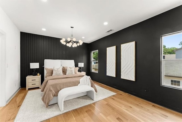 bedroom with an inviting chandelier, light wood-type flooring, and multiple windows