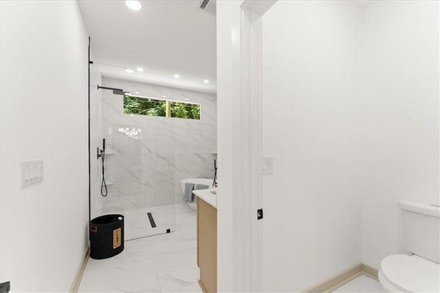 bathroom featuring a tile shower, vanity, and toilet