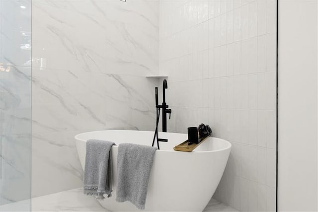 bathroom featuring a bath and tile walls