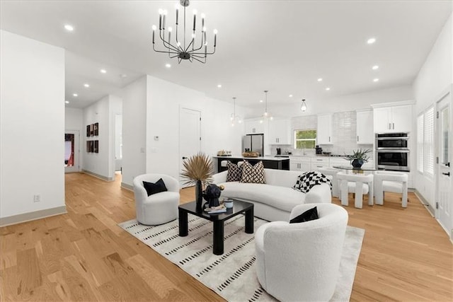 living room with an inviting chandelier and light hardwood / wood-style flooring