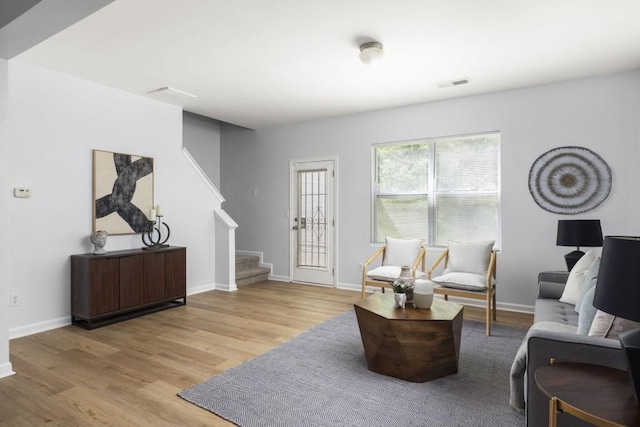 living area with stairway, light wood-style floors, and baseboards