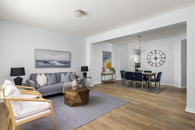 living room with wood finished floors, a chandelier, and baseboards