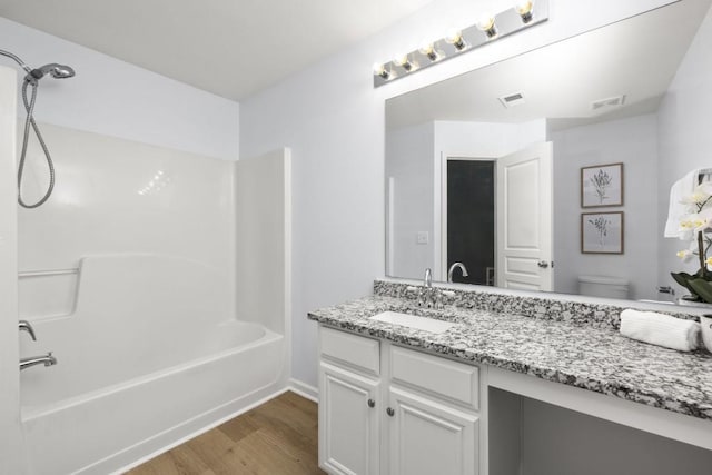 full bathroom featuring wood finished floors, toilet, vanity, tub / shower combination, and baseboards