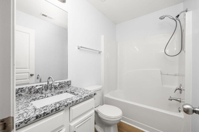 bathroom featuring toilet, vanity, and bathing tub / shower combination
