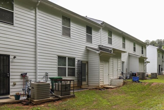 rear view of house with central air condition unit and a yard