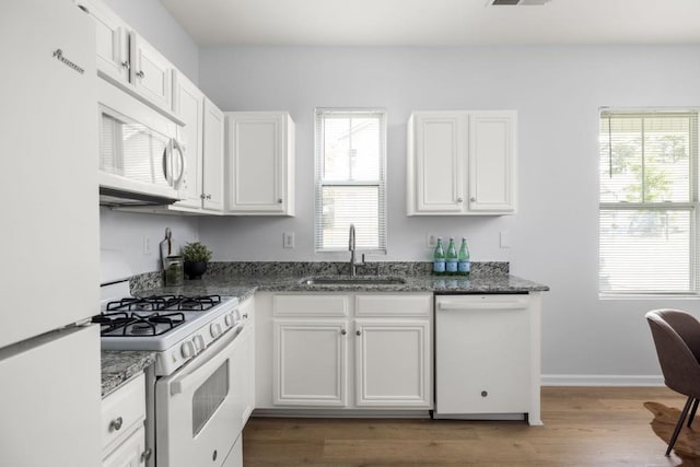 kitchen with white appliances, a sink, white cabinets, and dark stone countertops