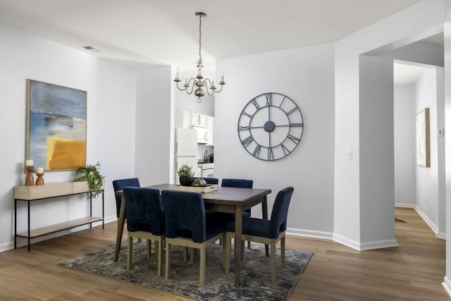 dining space with a chandelier, wood finished floors, and baseboards