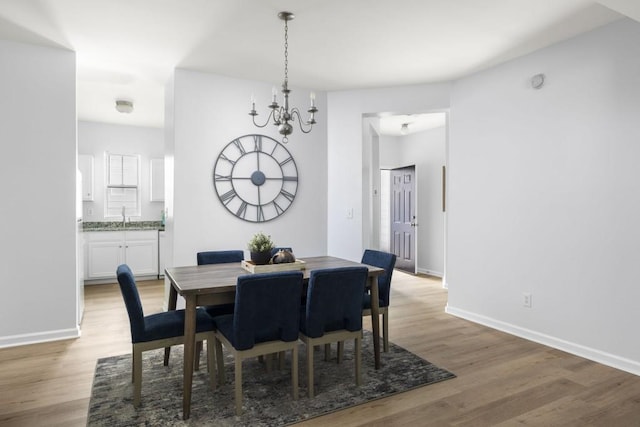 dining space featuring light wood-style floors, a chandelier, and baseboards