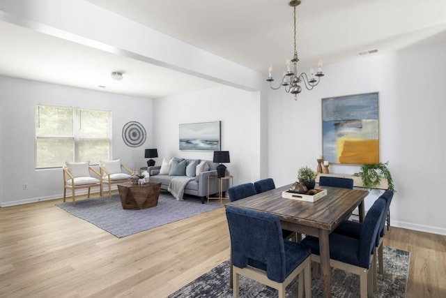 dining room featuring a chandelier, light wood-type flooring, and baseboards