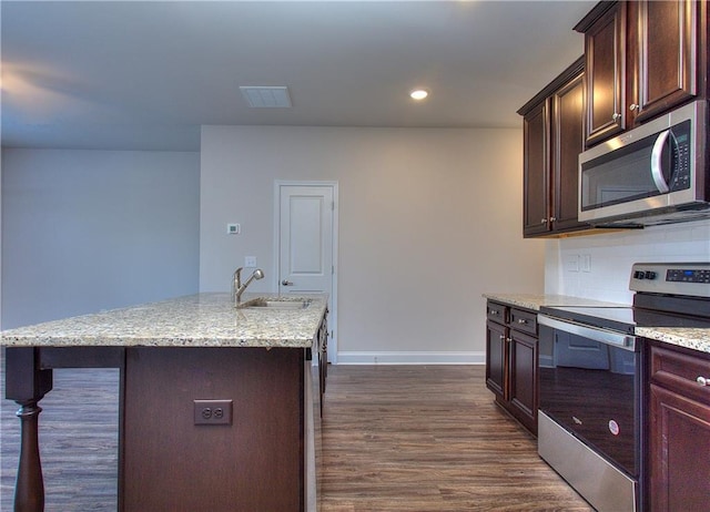 kitchen featuring a kitchen island with sink, appliances with stainless steel finishes, dark wood-type flooring, sink, and tasteful backsplash