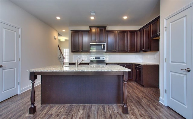 kitchen with stainless steel appliances, a kitchen island with sink, dark hardwood / wood-style floors, and dark brown cabinetry