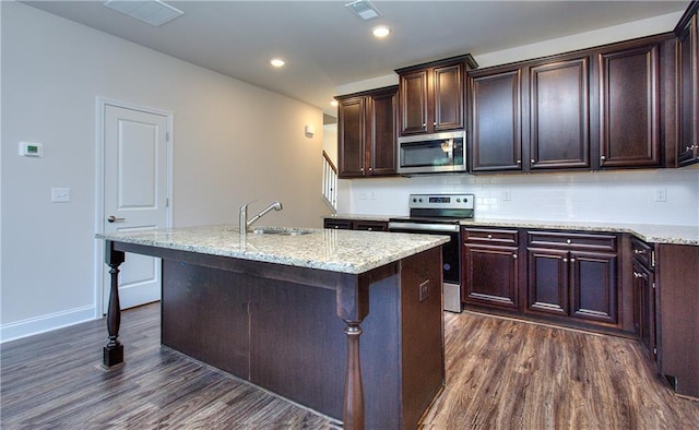 kitchen featuring a breakfast bar, a kitchen island with sink, dark hardwood / wood-style flooring, appliances with stainless steel finishes, and sink