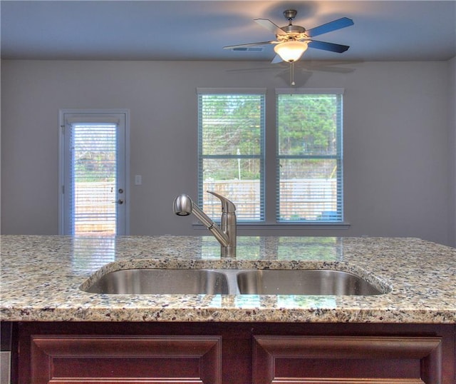 kitchen featuring light stone countertops, ceiling fan, and sink