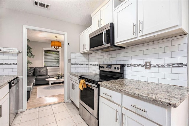8740 Roswell Rd Unit 2G, Atlanta, GA 30350 - kitchen featuring appliances with stainless steel finishes, white cabinetry, decorative backsplash, light tile patterned flooring, and light stone counters