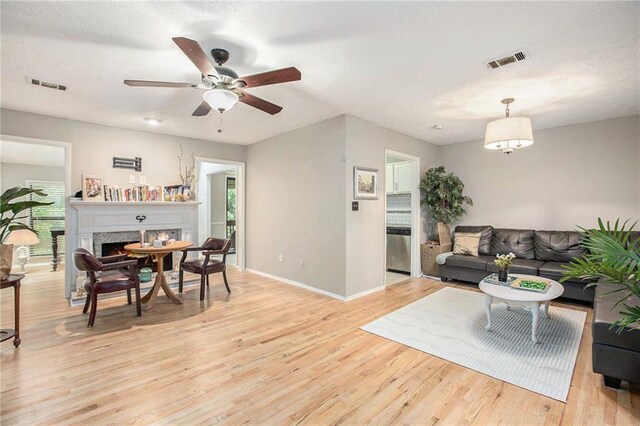 8740 Roswell Rd Unit 2G, Atlanta, GA 30350 - living room with light wood-style floors, ceiling fan, baseboards, and a warm lit fireplace