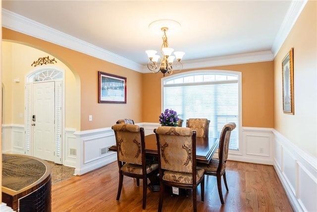 dining room featuring light hardwood / wood-style floors, an inviting chandelier, and ornamental molding