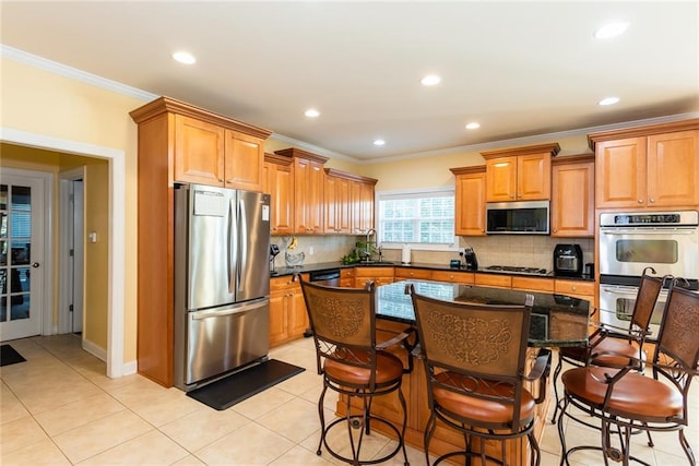 kitchen with a breakfast bar area, a center island, appliances with stainless steel finishes, and decorative backsplash