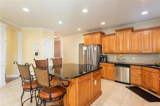 kitchen with dark stone countertops, ornate columns, stainless steel appliances, and a center island