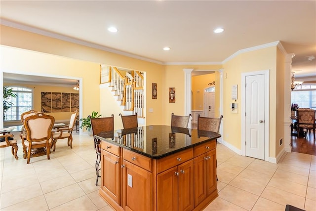 kitchen featuring crown molding, a center island, a healthy amount of sunlight, and dark stone countertops