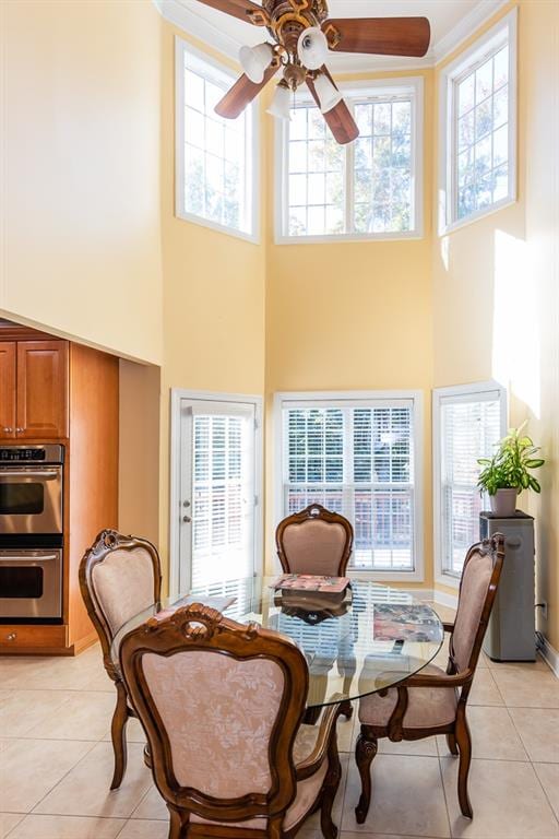 living area with ceiling fan, a high ceiling, and light tile patterned floors